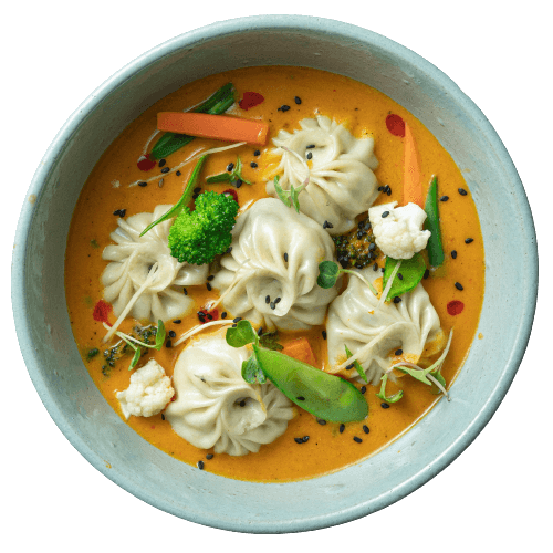 Squash soup with vegetarian dumplings accompanied with a drizzle of seeds and broccoli